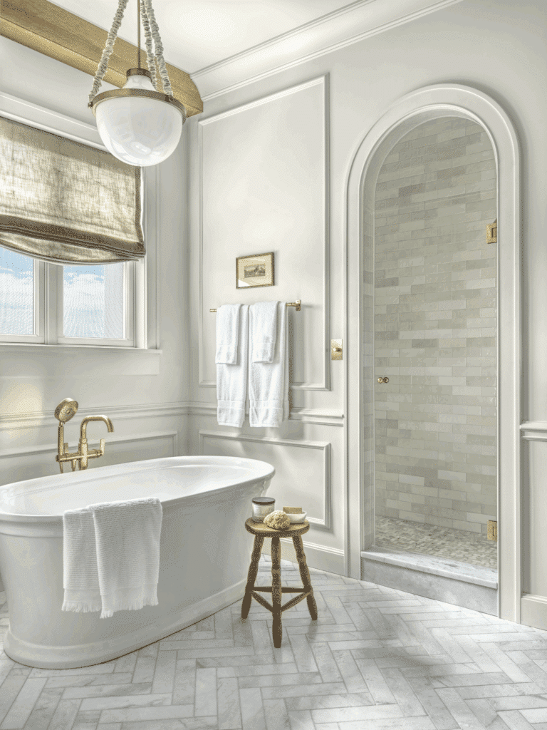 St. Charles bathroom remodel with freestanding tub, gold fixtures, herringbone marble floor, and arched shower.
