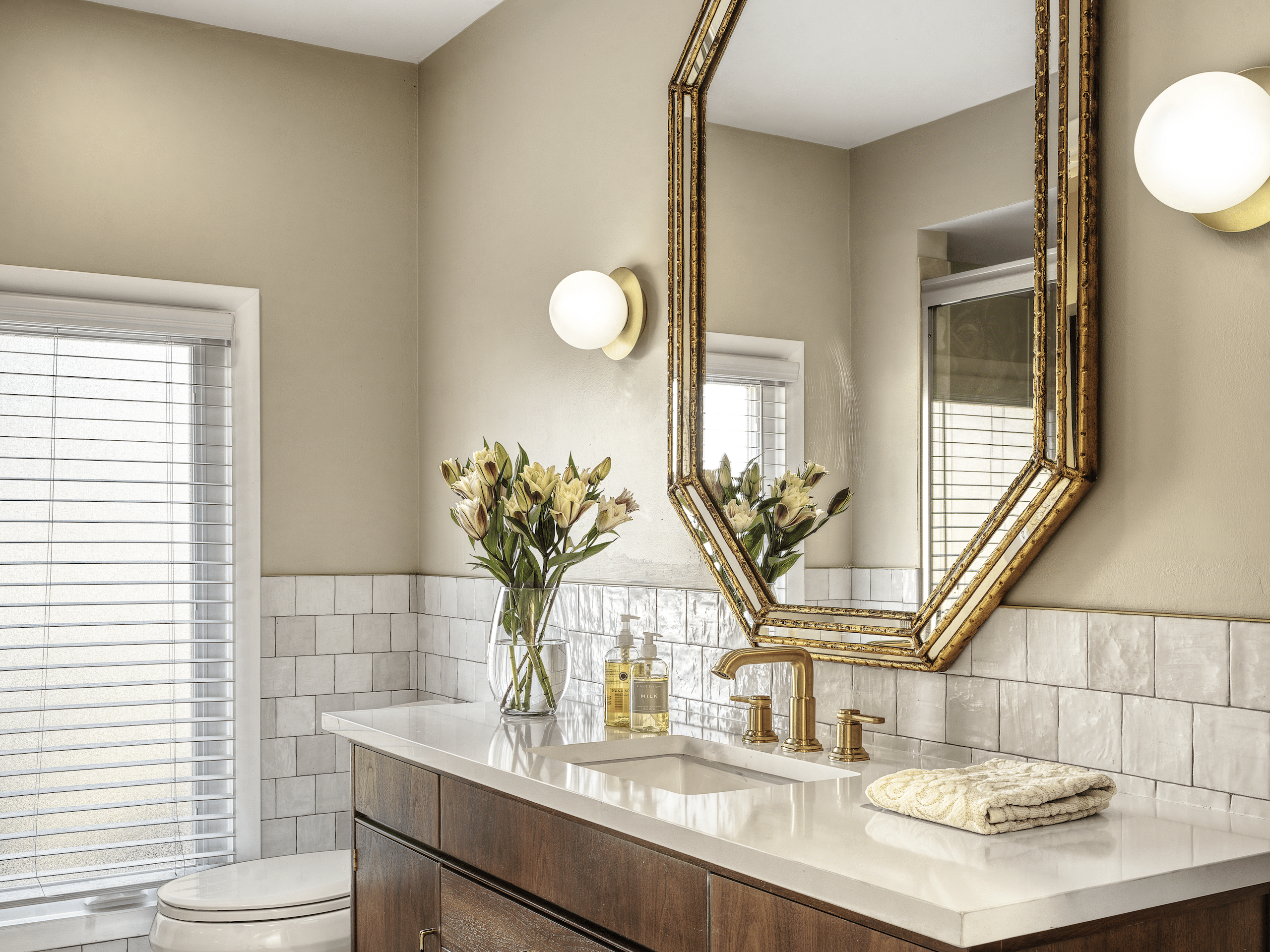 High end bathroom renovation in St. Charles, MO, featuring a custom vanity, gold fixtures, and warm wood cabinetry.
