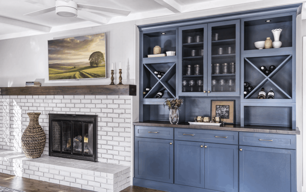 Blue built-in cabinetry unit next to a white brick fireplace with a dark wood mantel and mounted television.