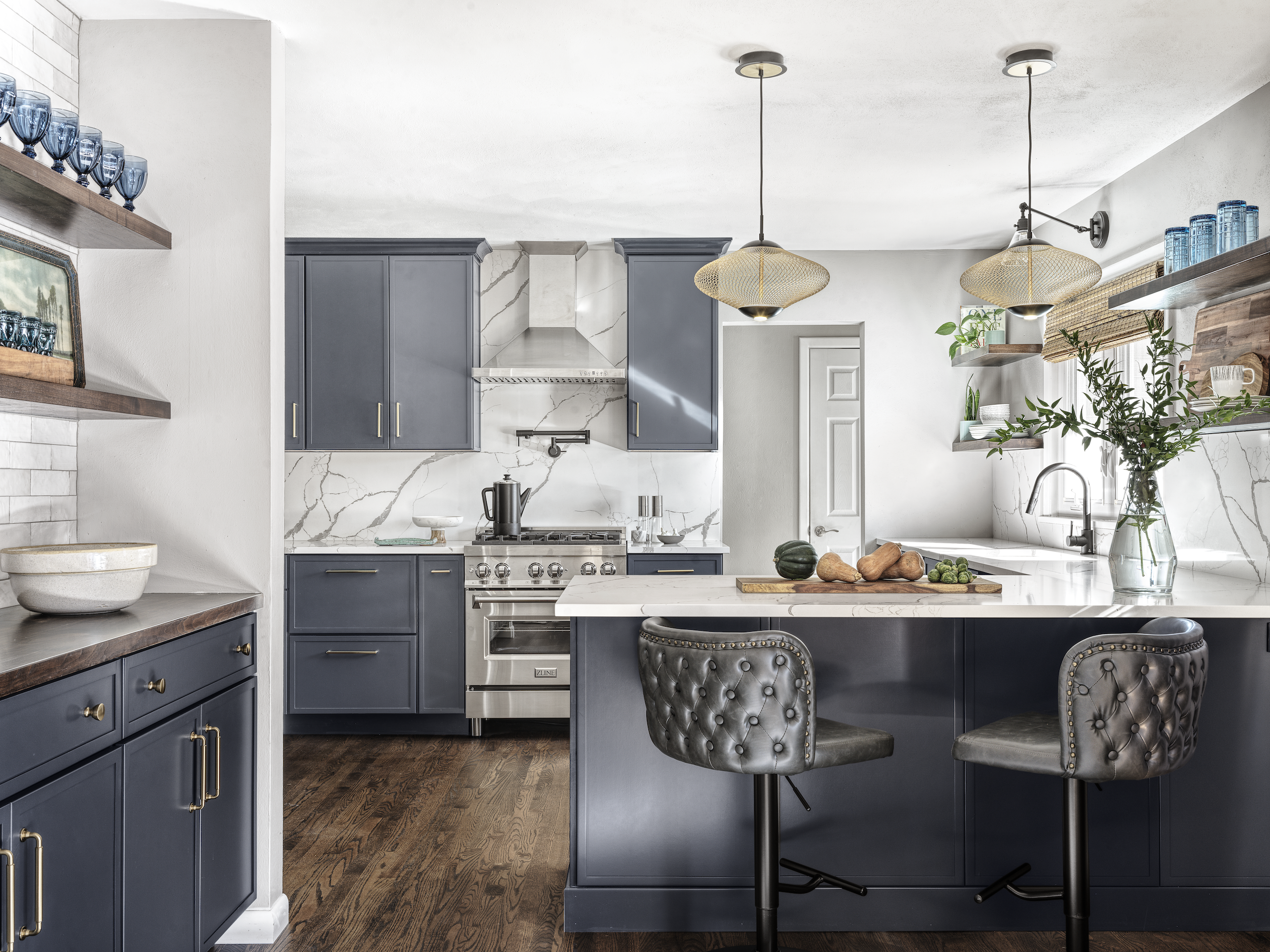 Kitchen remodel designed by a custom kitchen contractor St Louis, featuring blue shaker cabinets and a marble backsplash.