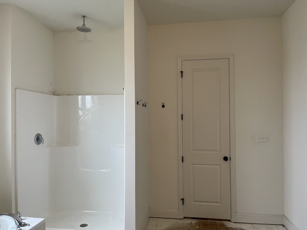 before photo of builder-grade bathroom with view of shower and doorway
