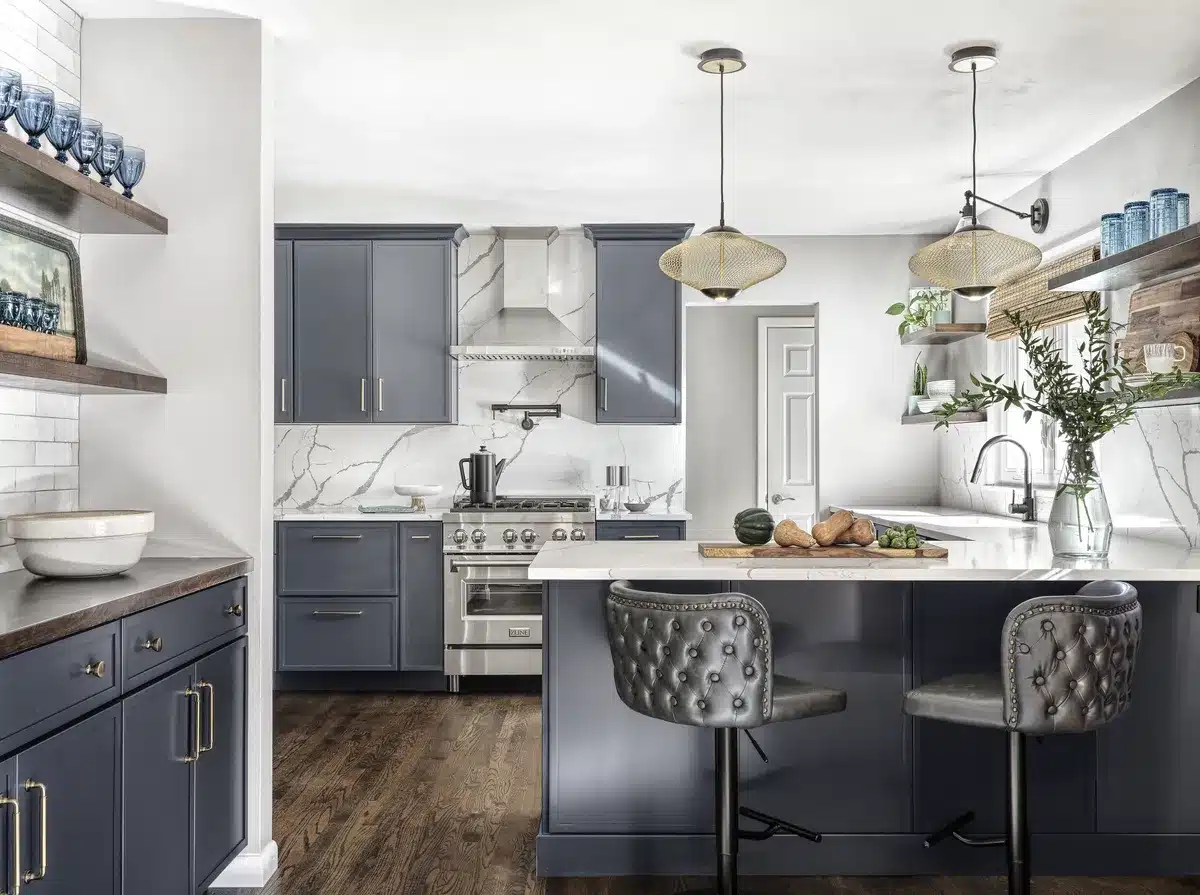 Kitchen remodel with navy shaker cabinets, marble backsplash, open wood shelving, and tufted leather counter stools.